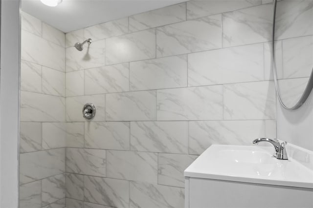 bathroom with a tile shower and vanity