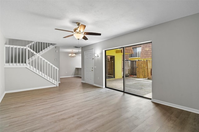 spare room featuring hardwood / wood-style flooring, ceiling fan with notable chandelier, and a textured ceiling