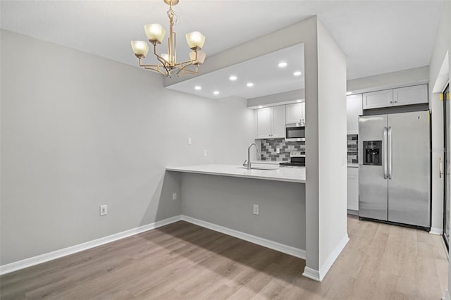 kitchen with sink, a notable chandelier, white cabinetry, stainless steel appliances, and decorative light fixtures