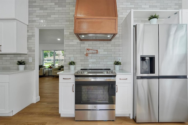 kitchen with backsplash, stainless steel appliances, light wood-type flooring, and white cabinetry