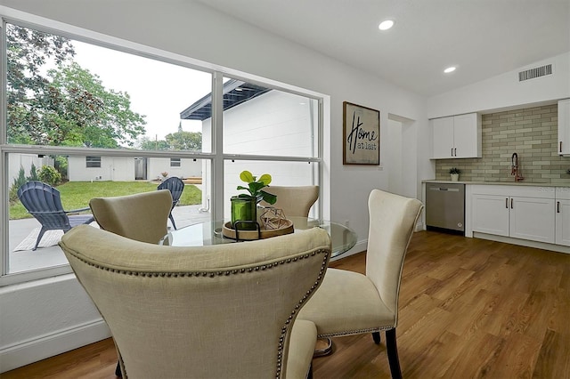 dining area featuring lofted ceiling, light wood-type flooring, and sink