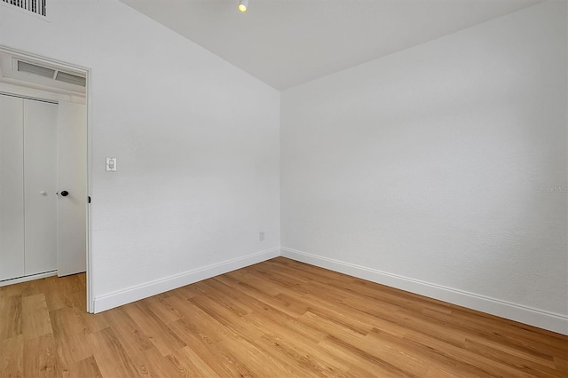 spare room featuring light hardwood / wood-style floors and vaulted ceiling