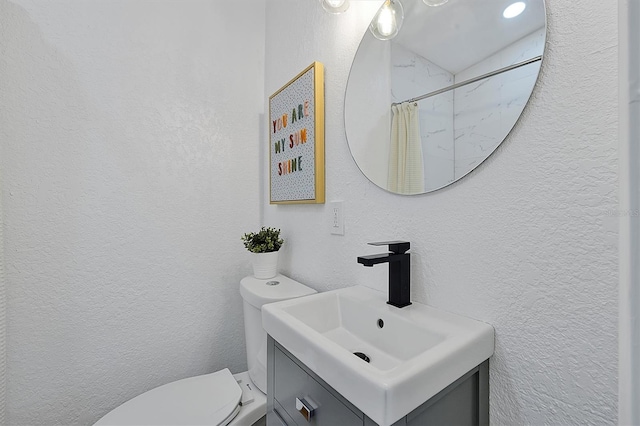 bathroom featuring curtained shower, toilet, and vanity