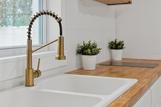 details with black electric cooktop, sink, and white cabinets