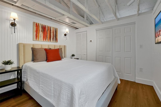 bedroom featuring wooden walls, dark hardwood / wood-style floors, and multiple closets