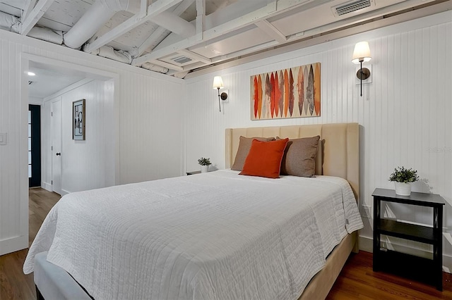 bedroom featuring wood walls, dark hardwood / wood-style floors, and beam ceiling