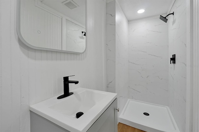 bathroom featuring tiled shower, hardwood / wood-style floors, and vanity