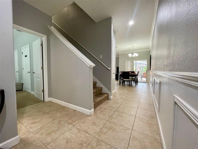 staircase with ornamental molding, tile patterned floors, and an inviting chandelier