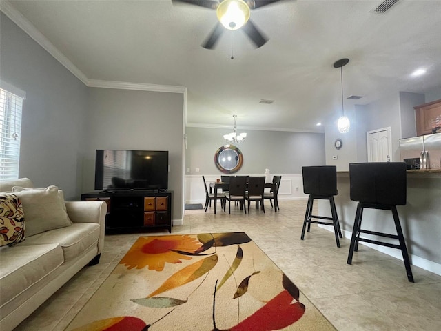 tiled living room with ceiling fan with notable chandelier and crown molding