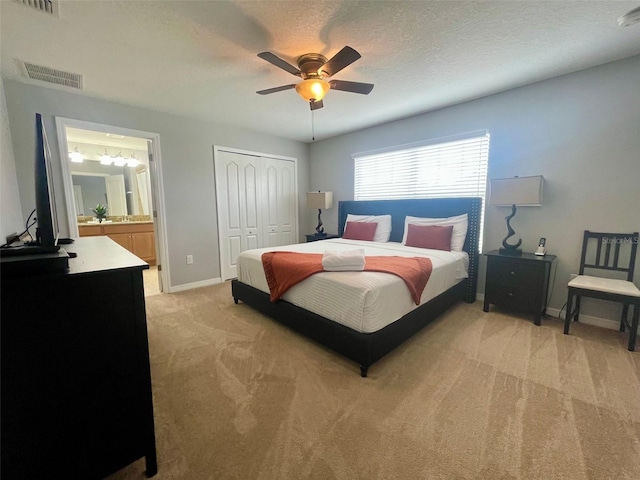 carpeted bedroom with a textured ceiling, ceiling fan, a closet, and ensuite bathroom