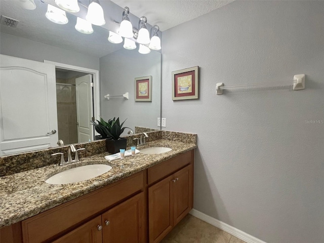 bathroom with tile patterned floors, a shower with shower door, a textured ceiling, and vanity