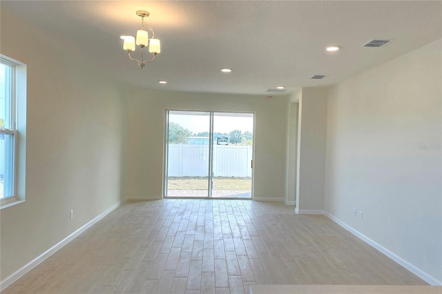 unfurnished room with an inviting chandelier and light wood-type flooring