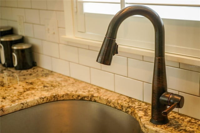 interior details with tasteful backsplash, light stone counters, and sink