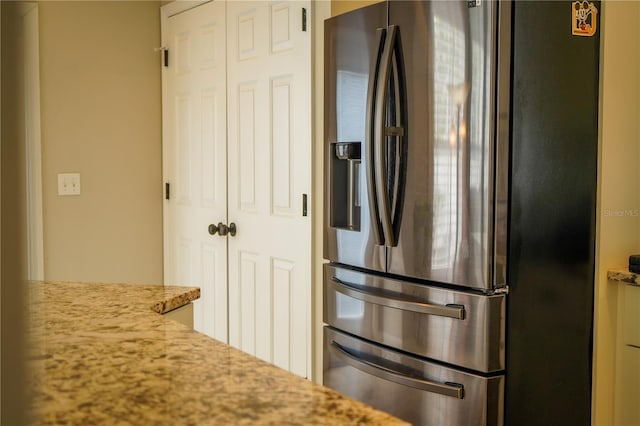 kitchen with light stone countertops and stainless steel refrigerator with ice dispenser