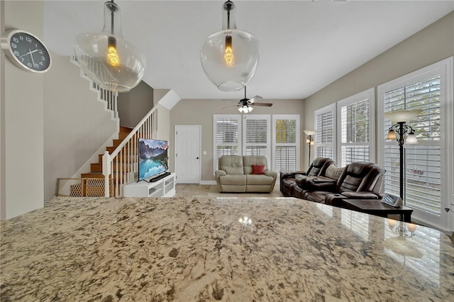 interior space with pendant lighting, ceiling fan, and light stone counters