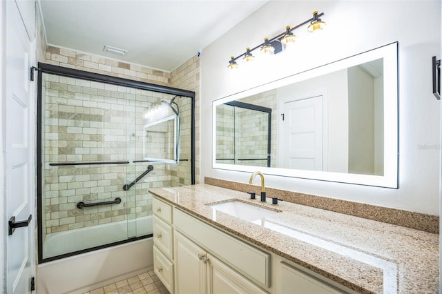 bathroom with tile patterned flooring, vanity, and bath / shower combo with glass door