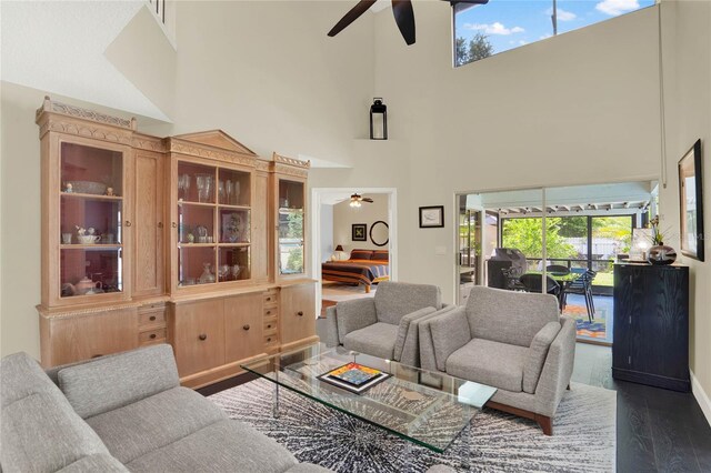 living room with a towering ceiling, ceiling fan, and dark hardwood / wood-style floors