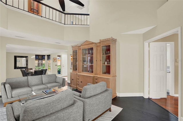 living room featuring a towering ceiling, dark hardwood / wood-style floors, and ceiling fan