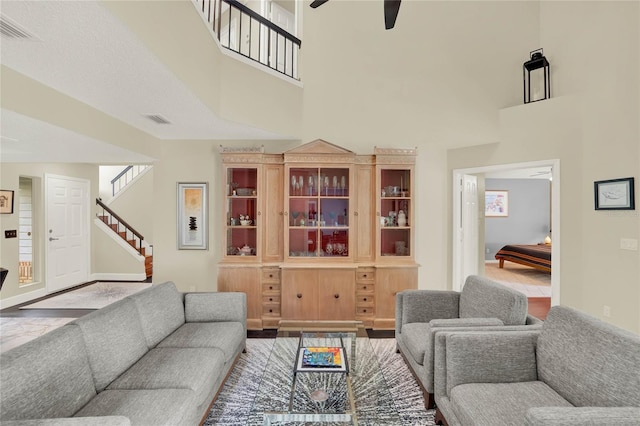 living room featuring a healthy amount of sunlight, a towering ceiling, and ceiling fan