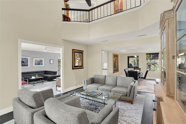 living room featuring a towering ceiling, ceiling fan, and hardwood / wood-style flooring