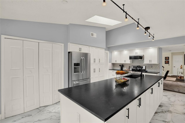 kitchen with white cabinets, a skylight, sink, stainless steel appliances, and decorative backsplash