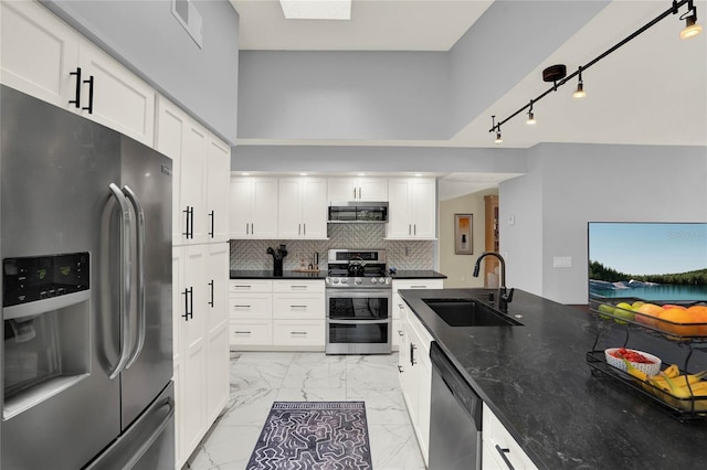 kitchen with appliances with stainless steel finishes, decorative backsplash, dark stone countertops, white cabinets, and sink