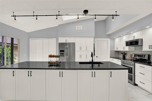 kitchen with a kitchen island with sink, sink, white cabinets, lofted ceiling, and appliances with stainless steel finishes