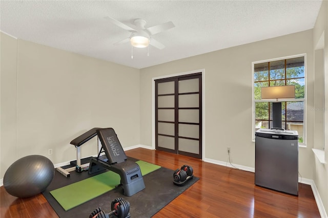 workout room featuring a textured ceiling, dark hardwood / wood-style floors, and ceiling fan