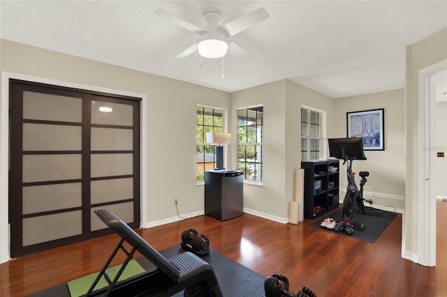 exercise room with a textured ceiling, dark hardwood / wood-style floors, and ceiling fan