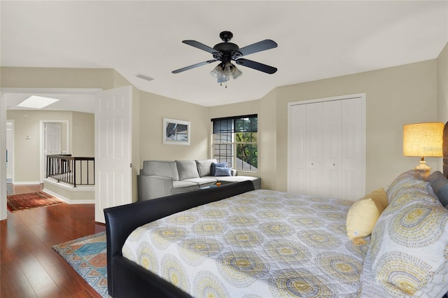 bedroom with ceiling fan, a skylight, a closet, and dark hardwood / wood-style floors