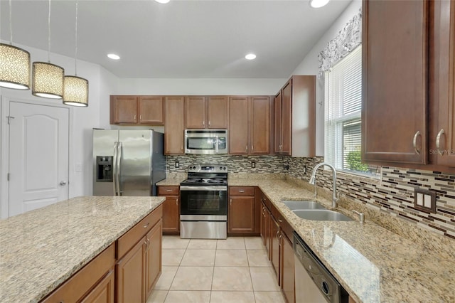 kitchen featuring backsplash, decorative light fixtures, sink, light stone countertops, and appliances with stainless steel finishes