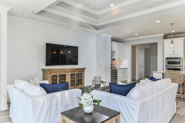 living room featuring crown molding, a raised ceiling, and light wood-type flooring