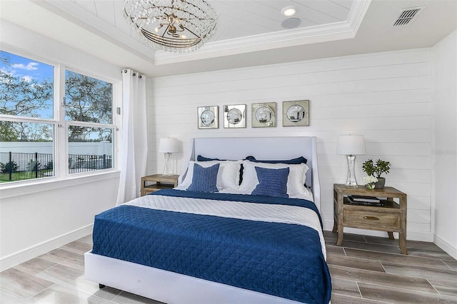 bedroom with a tray ceiling, wood-type flooring, and multiple windows