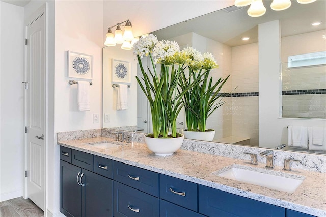 bathroom featuring vanity, hardwood / wood-style floors, and a tile shower