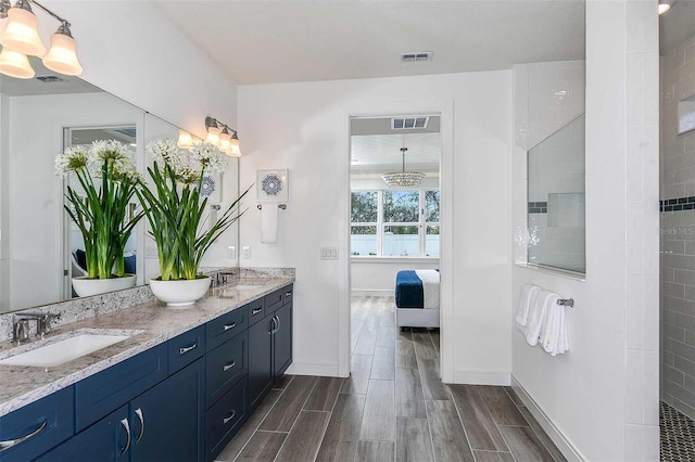 bathroom with vanity, a notable chandelier, hardwood / wood-style flooring, and a tile shower