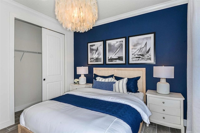 bedroom with dark wood-type flooring, a closet, crown molding, and a notable chandelier