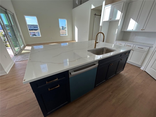 kitchen with white cabinetry, dishwasher, sink, a barn door, and a center island with sink