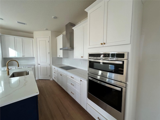 kitchen featuring white cabinets, black electric stovetop, double oven, and wall chimney range hood