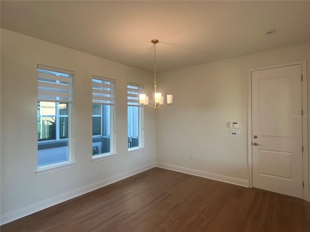 unfurnished dining area featuring an inviting chandelier and dark hardwood / wood-style flooring