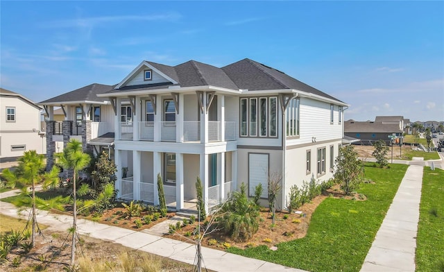 view of front of home featuring a balcony, a residential view, a front lawn, and roof with shingles