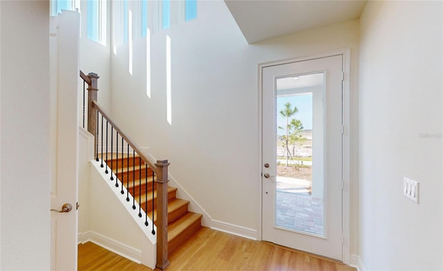 doorway to outside featuring light wood-style floors, stairs, and baseboards