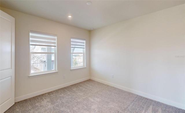 spare room with recessed lighting, light carpet, and baseboards