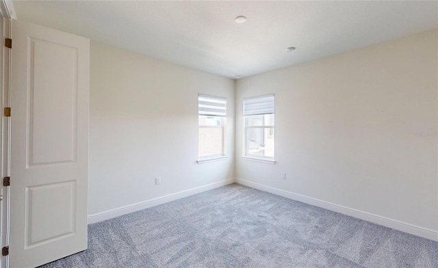 empty room featuring light carpet and baseboards