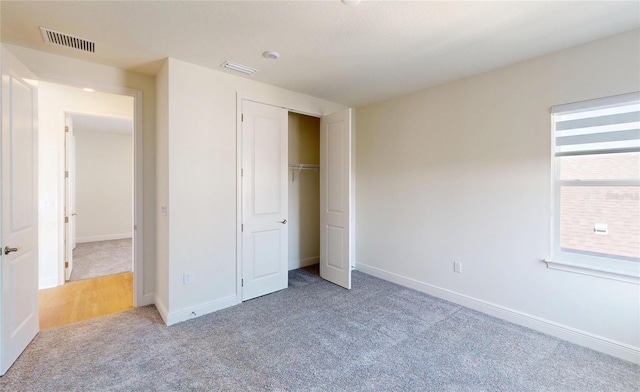 unfurnished bedroom featuring a closet, light colored carpet, visible vents, and baseboards