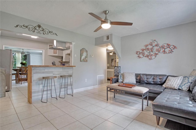 living room with ceiling fan, a textured ceiling, and light tile patterned floors