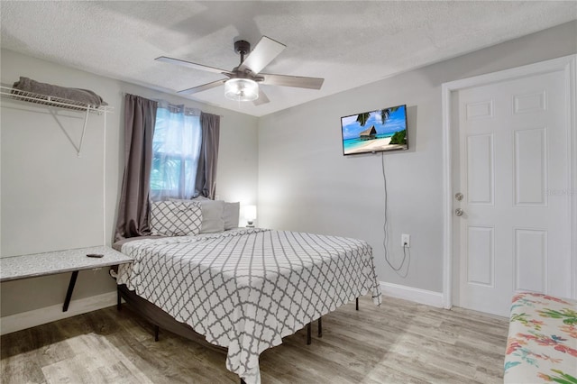 bedroom with ceiling fan, a textured ceiling, and hardwood / wood-style floors