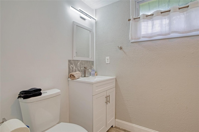 bathroom featuring vanity, toilet, and tasteful backsplash