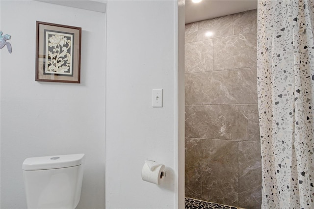 bathroom featuring toilet and curtained shower