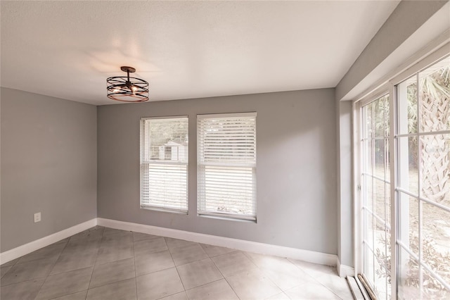 tiled spare room with a notable chandelier and a healthy amount of sunlight