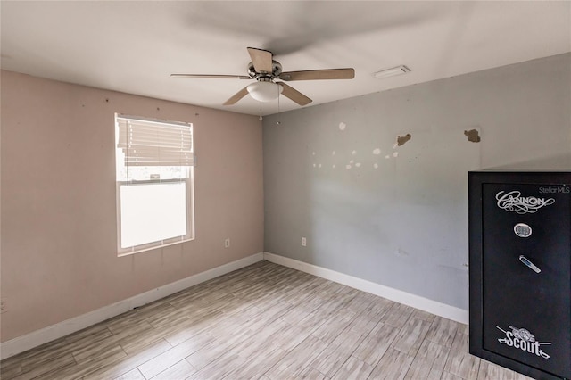 spare room featuring baseboards, wood finished floors, and a ceiling fan